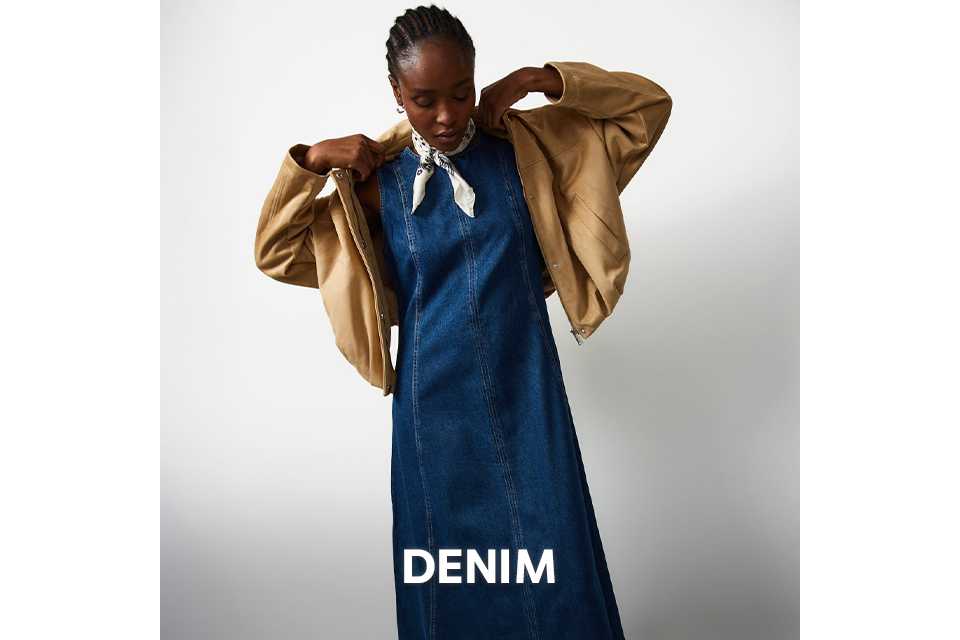 Denim midi dress styled with a cropped neutral jacket and pointed‑toe heels.