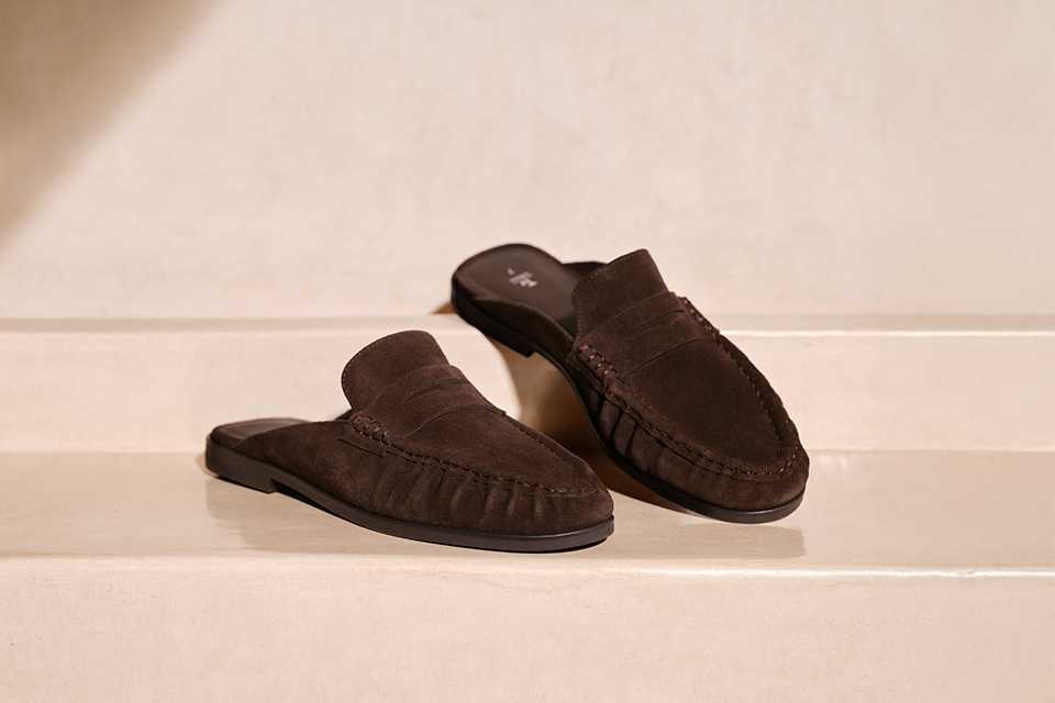 A cut out image of brown flat slip on loafers.