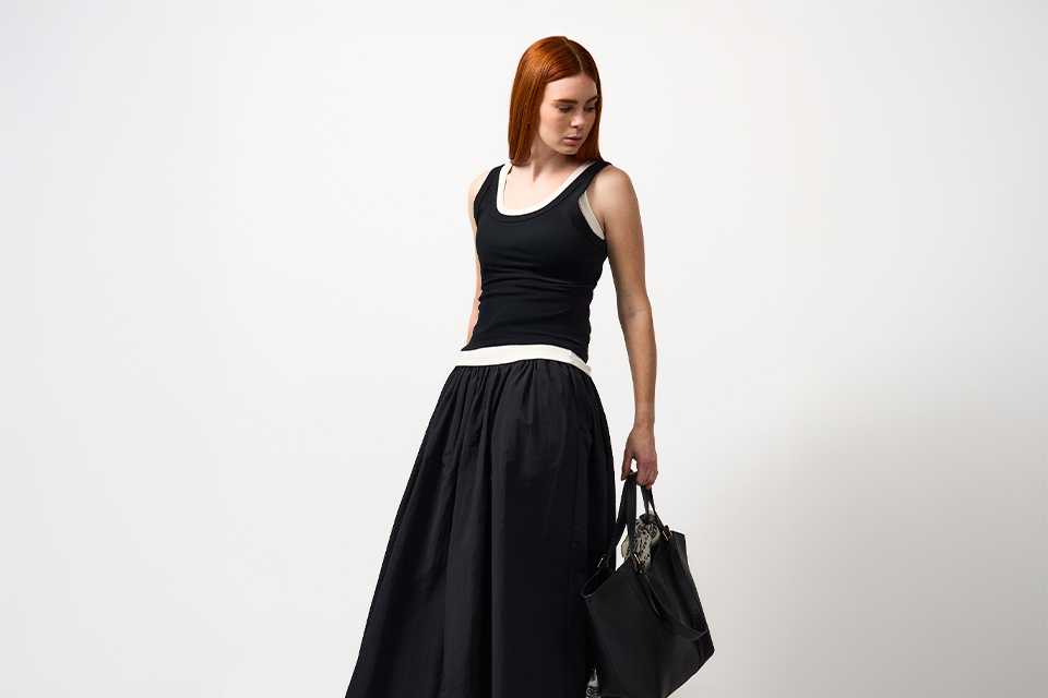 Black midi dress styled with minimal accessories, showcasing a versatile spring outfit with a clean, modern silhouette.