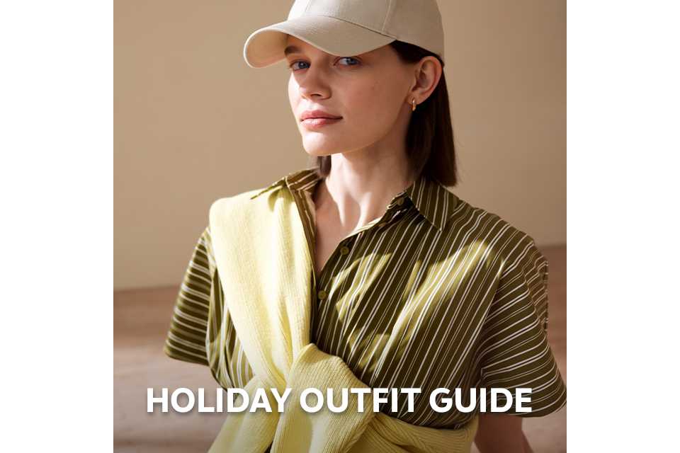 Person wearing a green striped shirt dress with a yellow knit sweater styled over the shoulders.