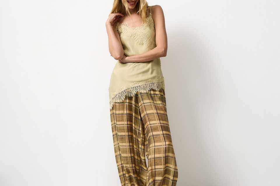 Light summer outfit featuring a sleeveless top paired with neutral trousers, showcasing an effortless warm‑weather look.