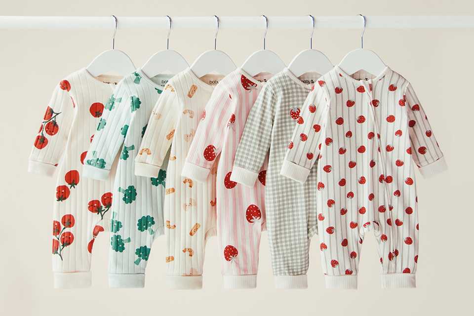 Newborn sleepsuits in soft cotton prints on hangers.