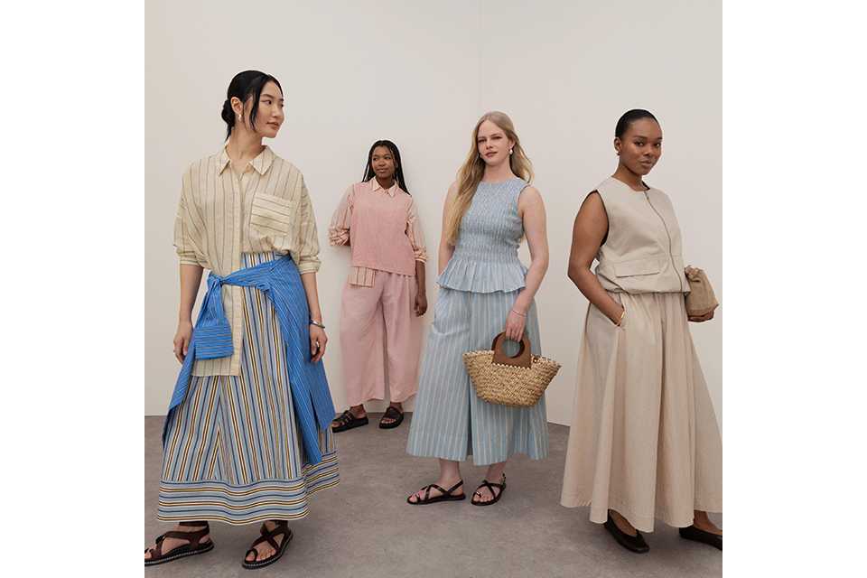 A women wearing white linen trousers and white top with a longline burgundy shirt.