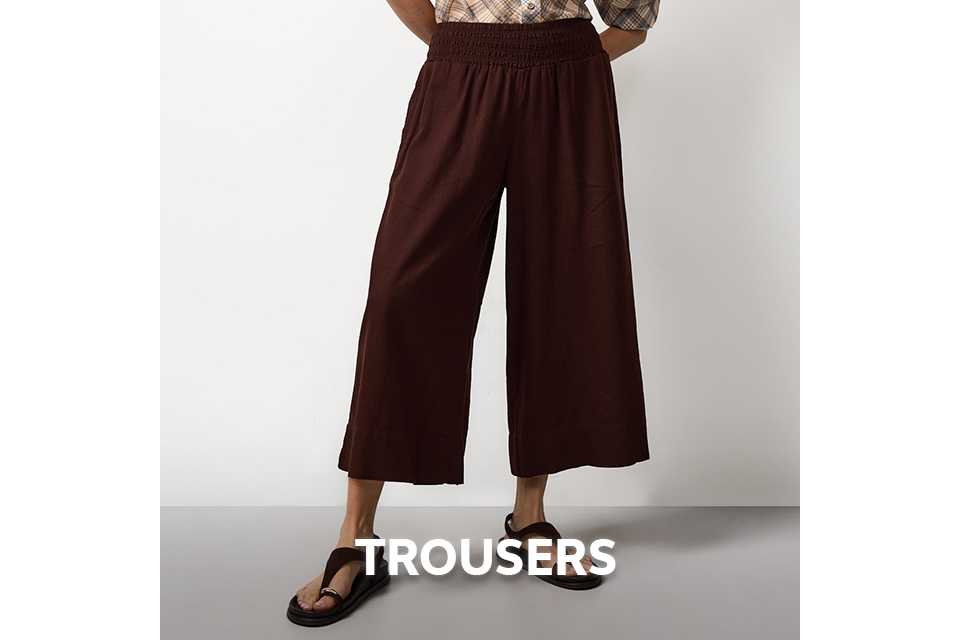 Woman wearing brown wide leg cropped trousers and a check shirt.