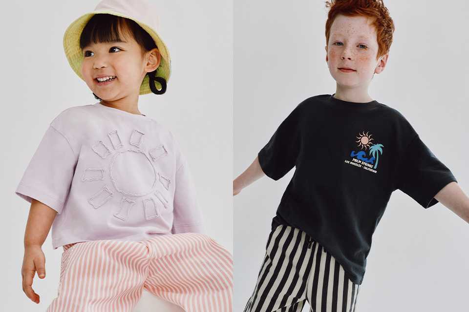 Child in a pink heart-print fleece with blue jeans, next to another child wearing a blue-and-beige striped top and jeans.