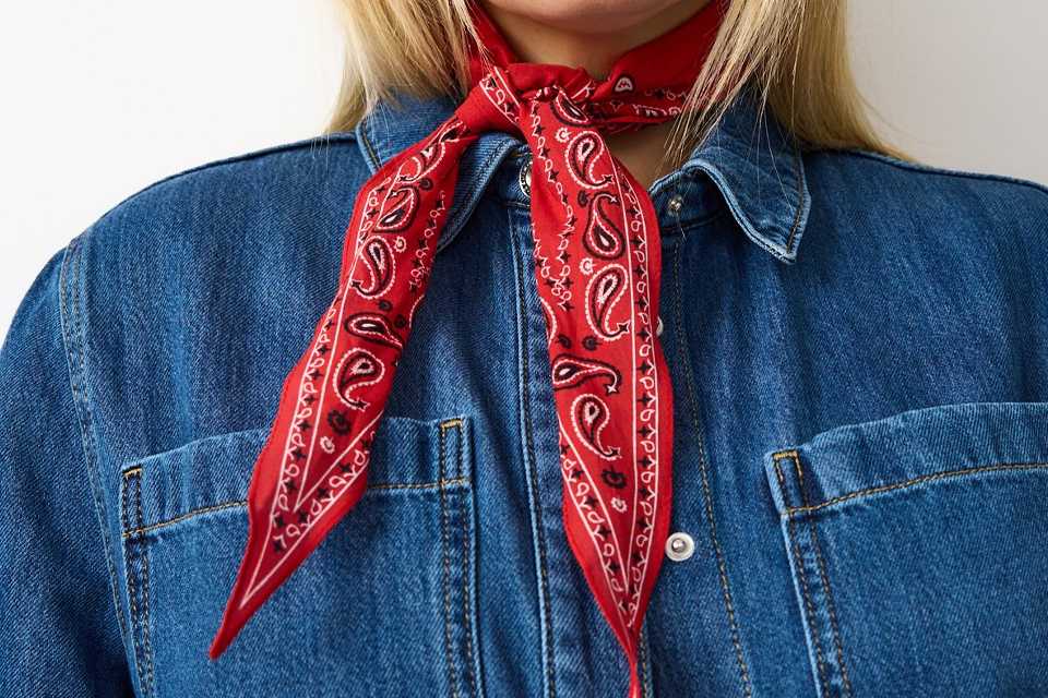 Denim jacket styled with a red patterned scarf, showing festival accessories for layered summer looks.