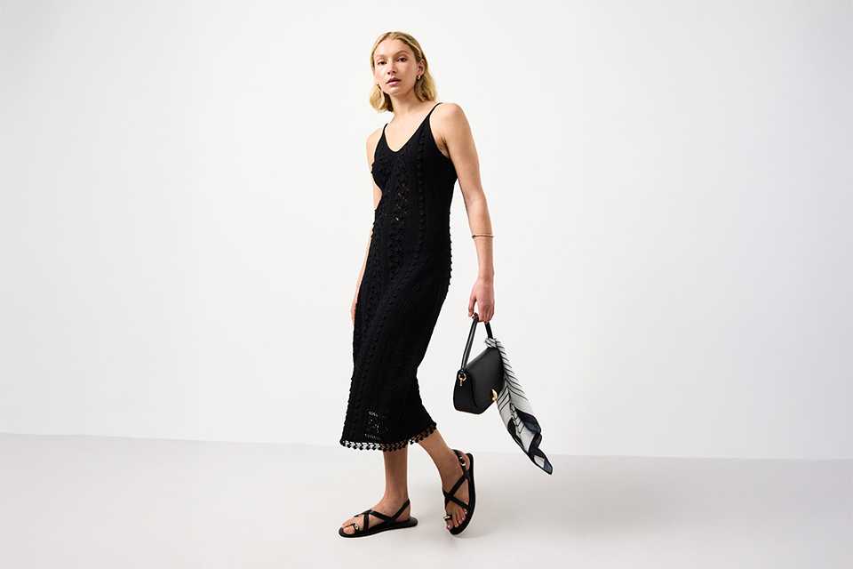 Black festival dress styled with sandals and small shoulder bag for a relaxed day-to-night festival outfit.