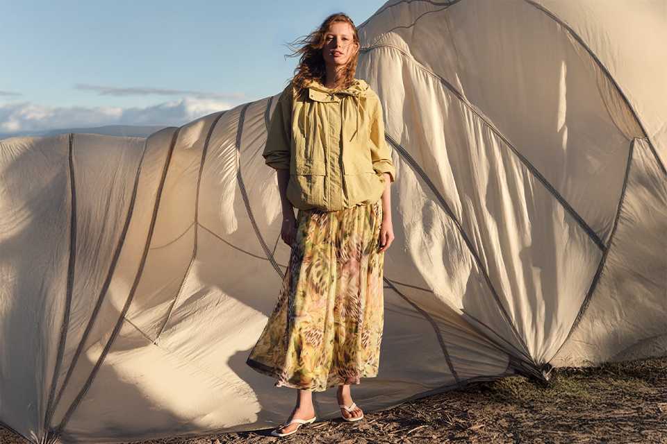 Lightweight jacket layered over a printed dress for comfortable summer styling.