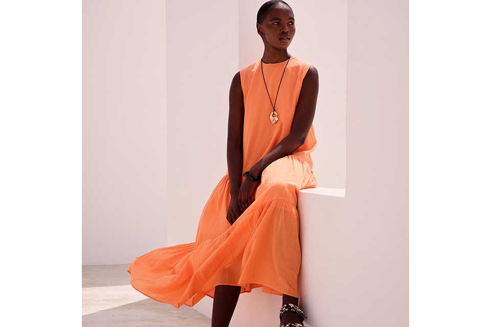 Coral sleeveless top and flowing midi skirt styled for summer trends and new season collections.