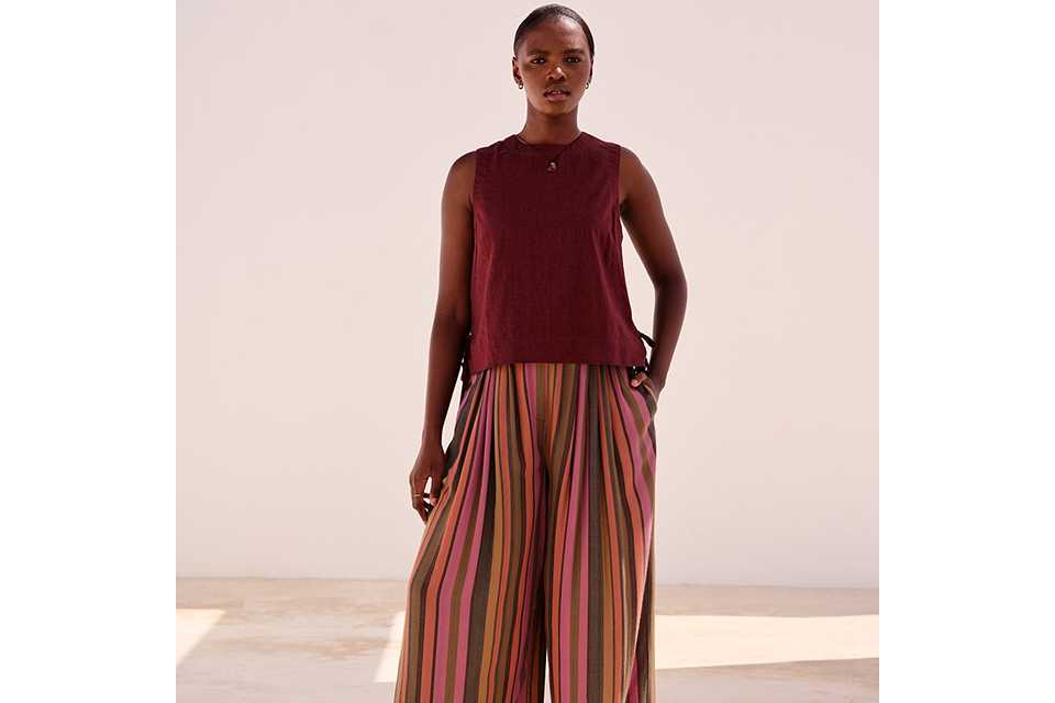 Burgundy sleeveless top styled with striped wide-leg trousers for summer outfit inspiration.