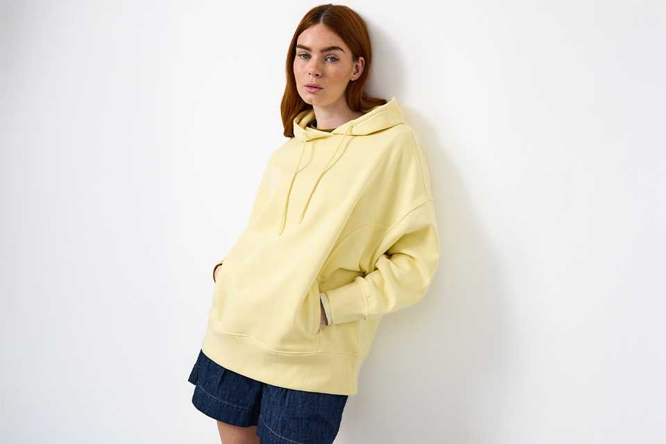 Yellow hoodie styled with denim skirt for casual UK staycation packing outfit.