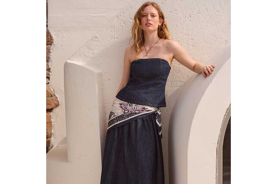 Woman wearing a denim co-ord with strapless top and maxi skirt.