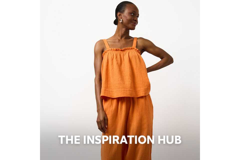 Woman wearing double cloth orange co ord, with orange wide leg trousers and orange cami top.
