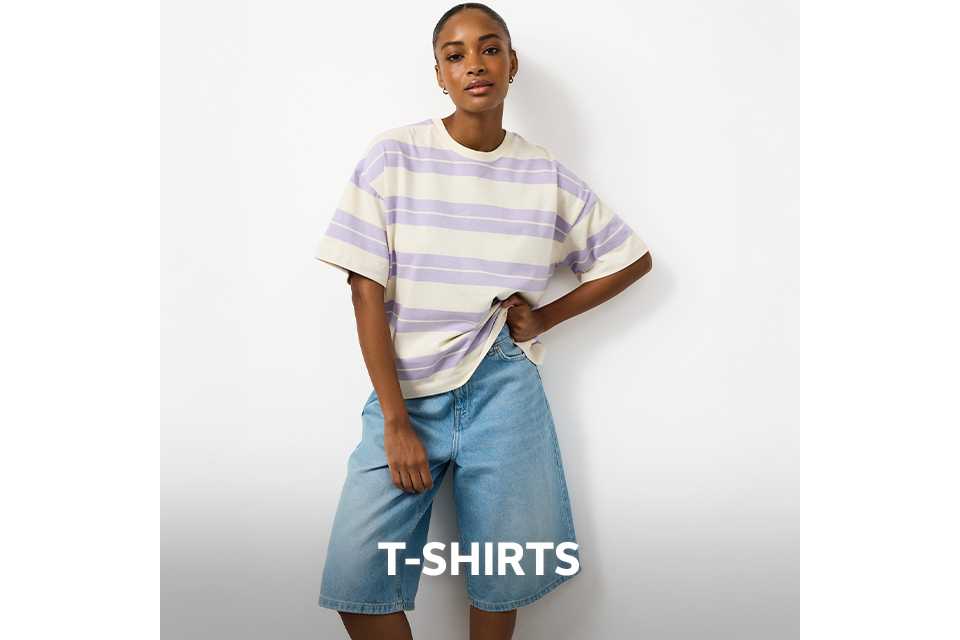 Woman wearing a lilac and cream strip t-shirt with light denim jorts.