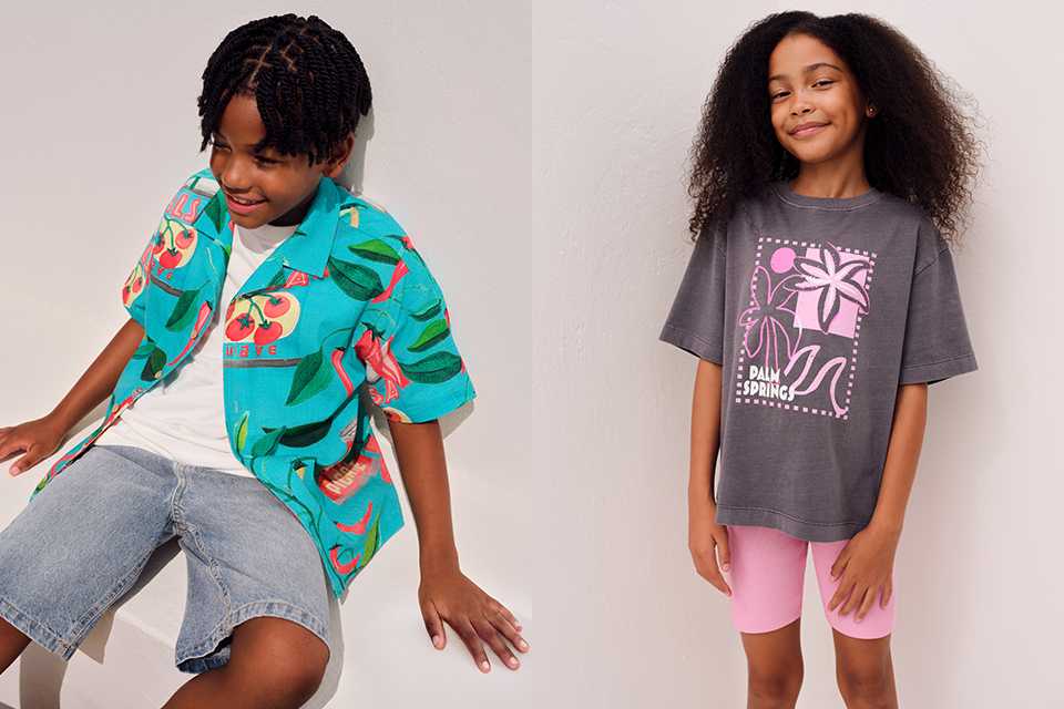 A picture showing two children, one with a girl wearing pink cycling shorts and a grey top, and another with a boy wearing a bright shirt, white tee and denim shorts.
