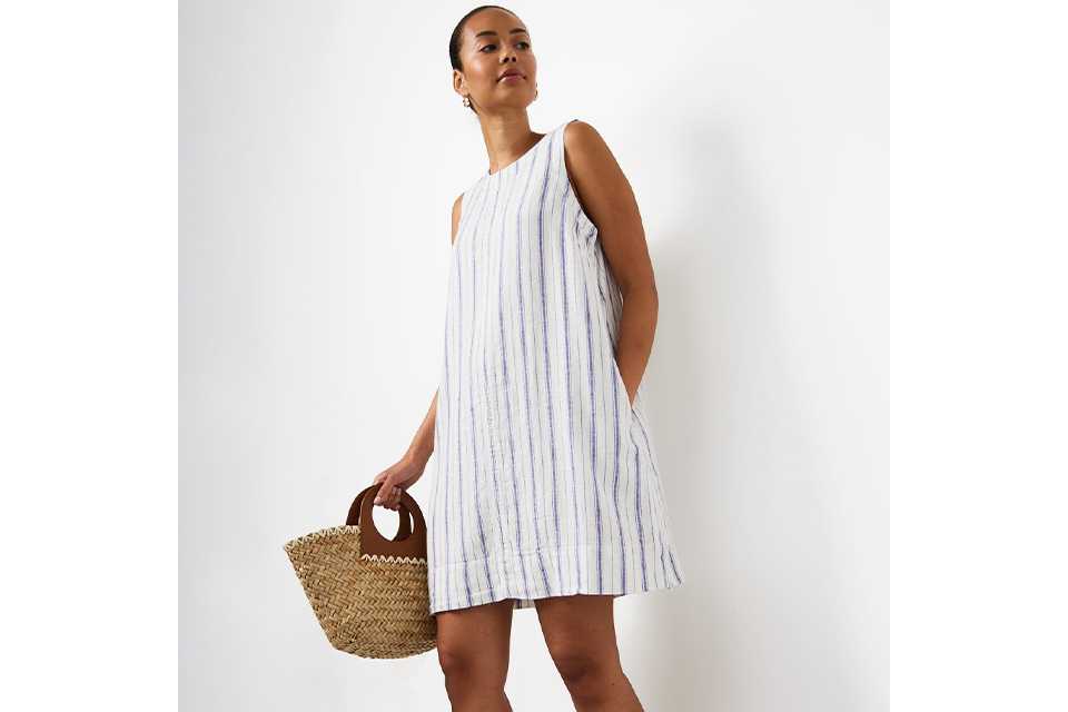 Woman wearing white linen mini dress with blue stripes.