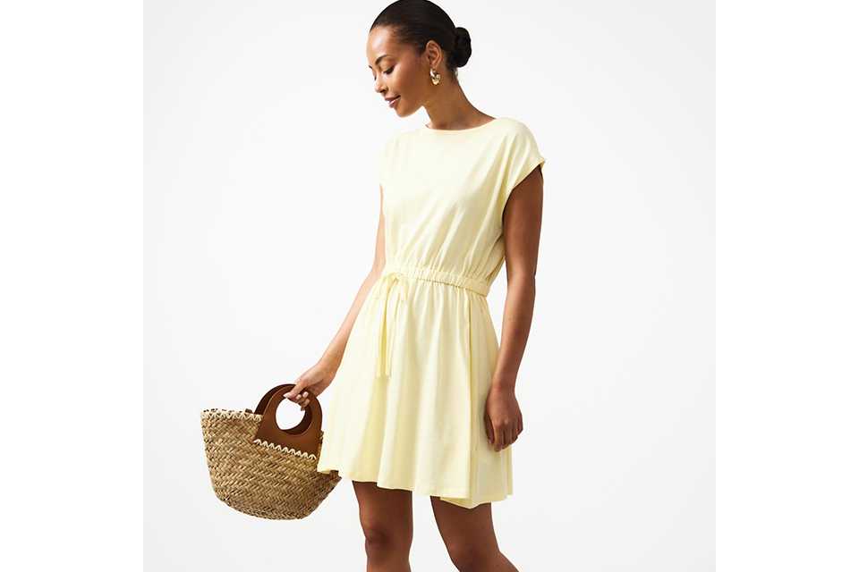 Woman wearing a butter yellow mini dress.
