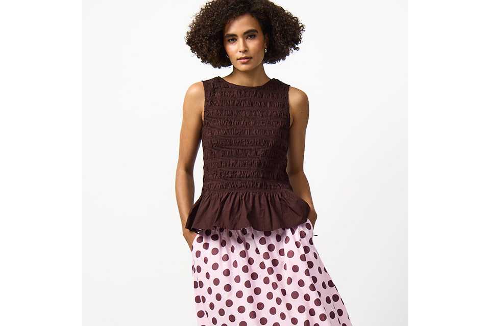 A woman wearing a polka dot skirt, paired with a brown sleeveless top.