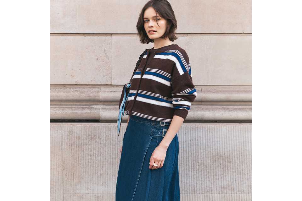 Woman wearing maxi denim skirt, with white ballet flats, and a stripey top.