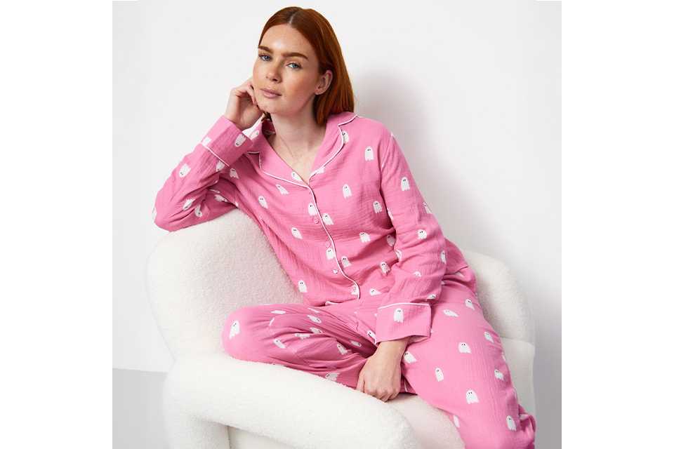 A woman wearing pink pyjamas with white ghosts on them.