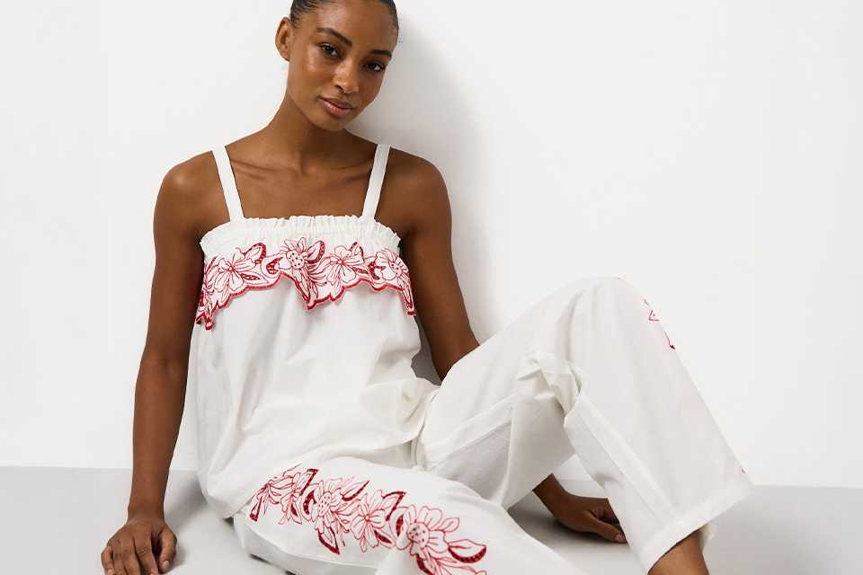 White embroidered co-ord set featuring a strappy camisole top and wide-leg trousers with red floral embroidery detailing and a relaxed fit.