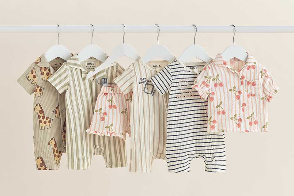 Children's swimwear set featuring a red gingham long-sleeve rash vest with strawberry applique, blue lobster-print swim shorts, and a striped strawberry-print ruffle swimsuit, displayed on a neutral background.