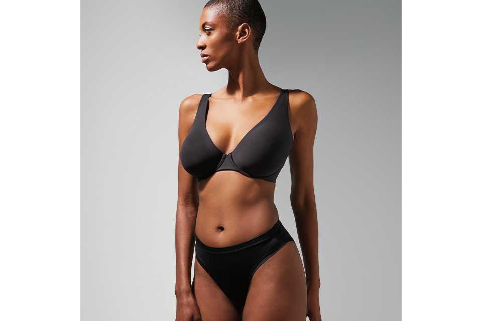 A woman wearing a black flexform bra which is designed to offer light support for everyday wear.