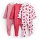 Three baby sleepsuits hanging on white hangers, including a red and white striped design, a plain pink design, and a white strawberry-print design with "Bon Appetit" text.