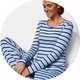 Light blue striped pajama set with matching lounge pants and grey slippers in a studio setting.