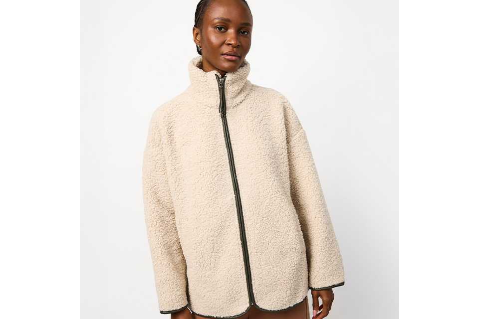 A woman wearing a borg, cream fluffy zip up jacket.