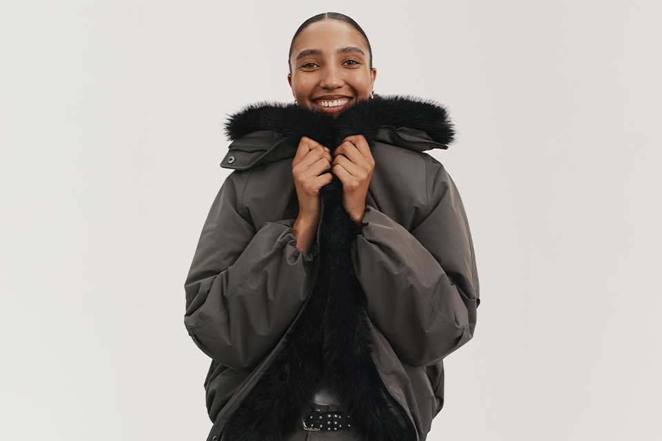 A woman wearing a pffa jacket with faux fur and khaki jeans.