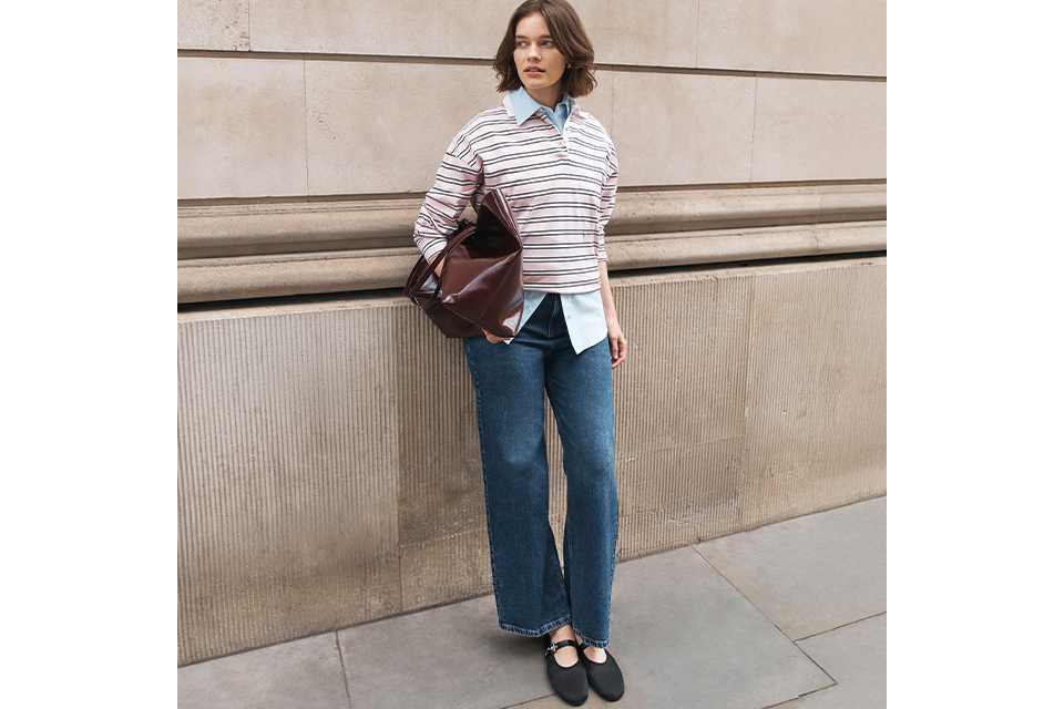 Striped rugby-style knit top layered over a blue collared shirt, paired with straight-leg denim jeans and black Mary Jane flats.