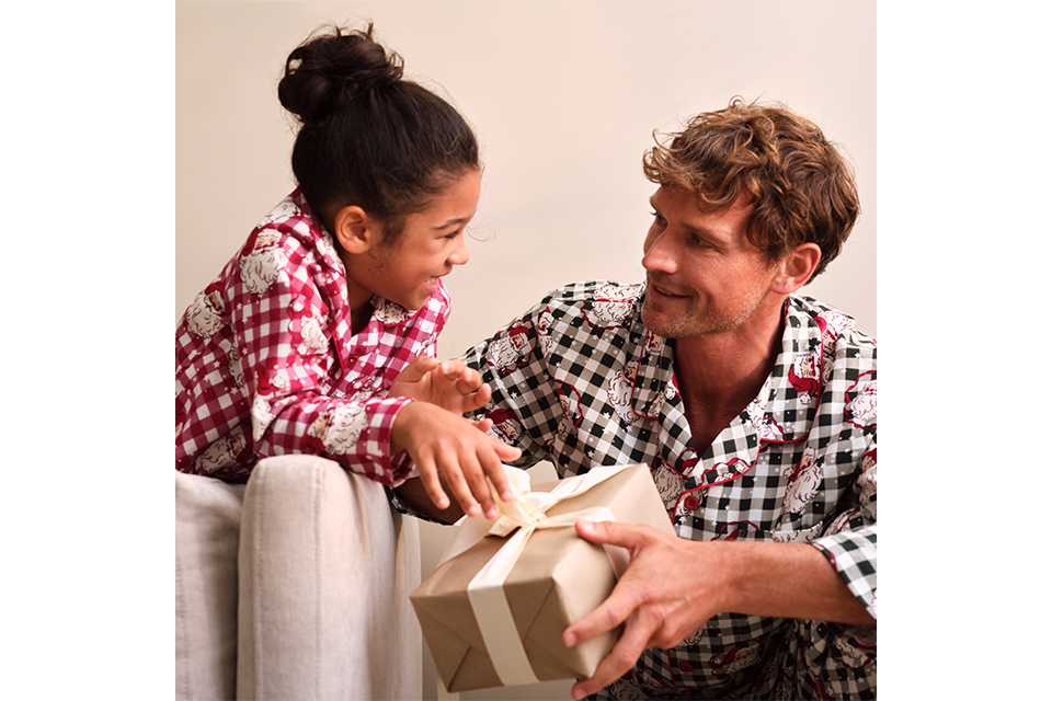 Family wearing matching novelty Christmas pyjamas with festive check prints and Christmas gift boxes.