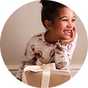 Child wearing festive Christmas pyjamas beside a Christmas Eve gift box.