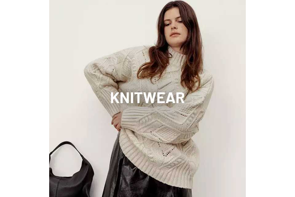 Woman wearing a cream knitted jumper and PU skirt.