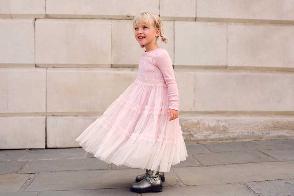 Girls' blush pink tiered tulle dress with long sleeves, smocked bodice and flowing maxi-length skirt.