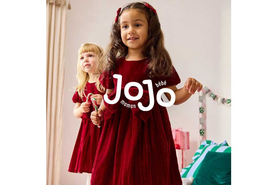 Two children wearing red velvet dresses with bows.