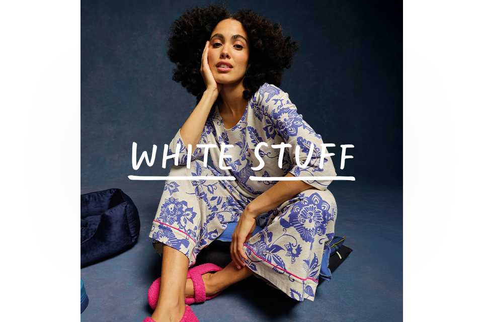 A woman wearing pyjamas with blue flowers and bright pink slippers.