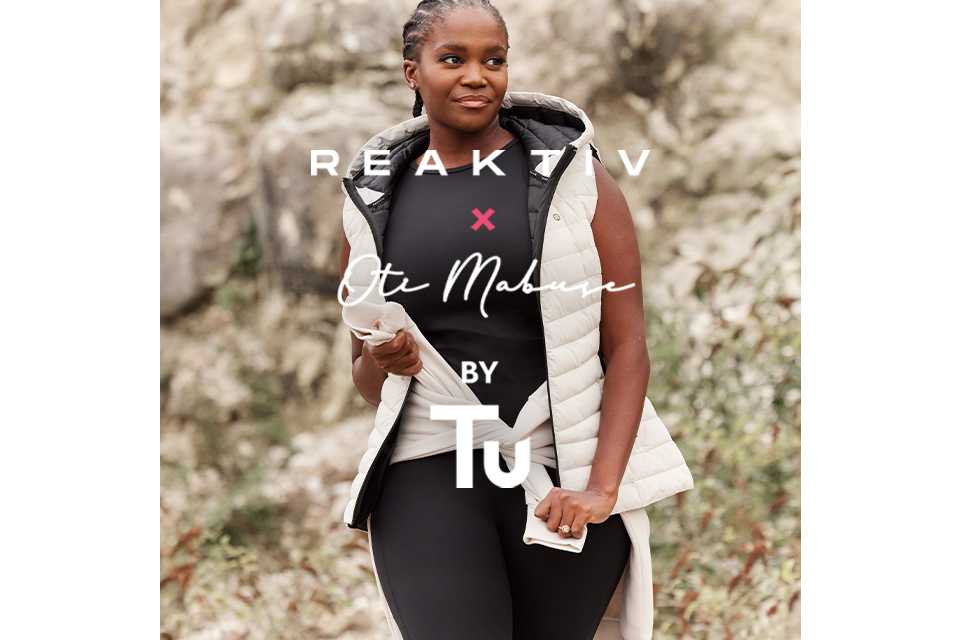 A woman wearing black top and black leggings, with a cream gilet and a cream jumper tied around her waist.