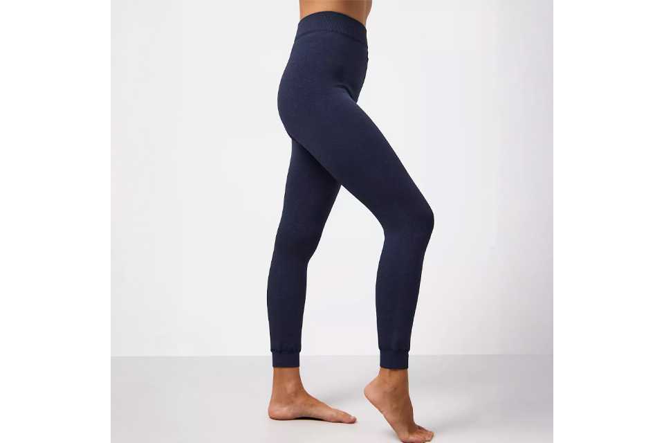 Person wearing slim-fit thermal leggings in dark navy blue, standing barefoot against a light background.