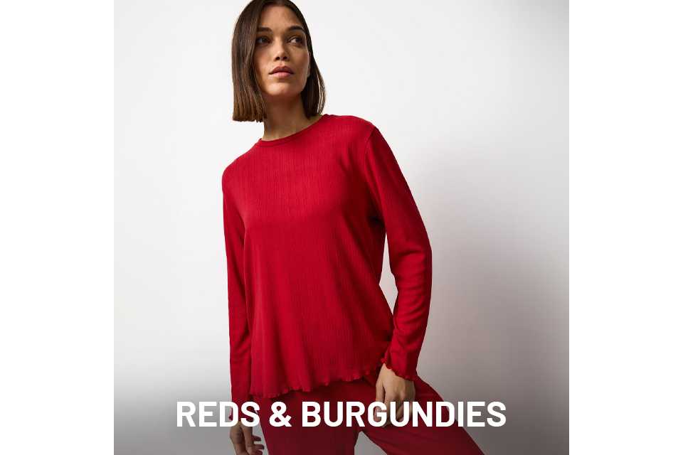 Person wearing a matching red ribbed loungewear set with a long-sleeve top and straight-leg pants against a plain white background.