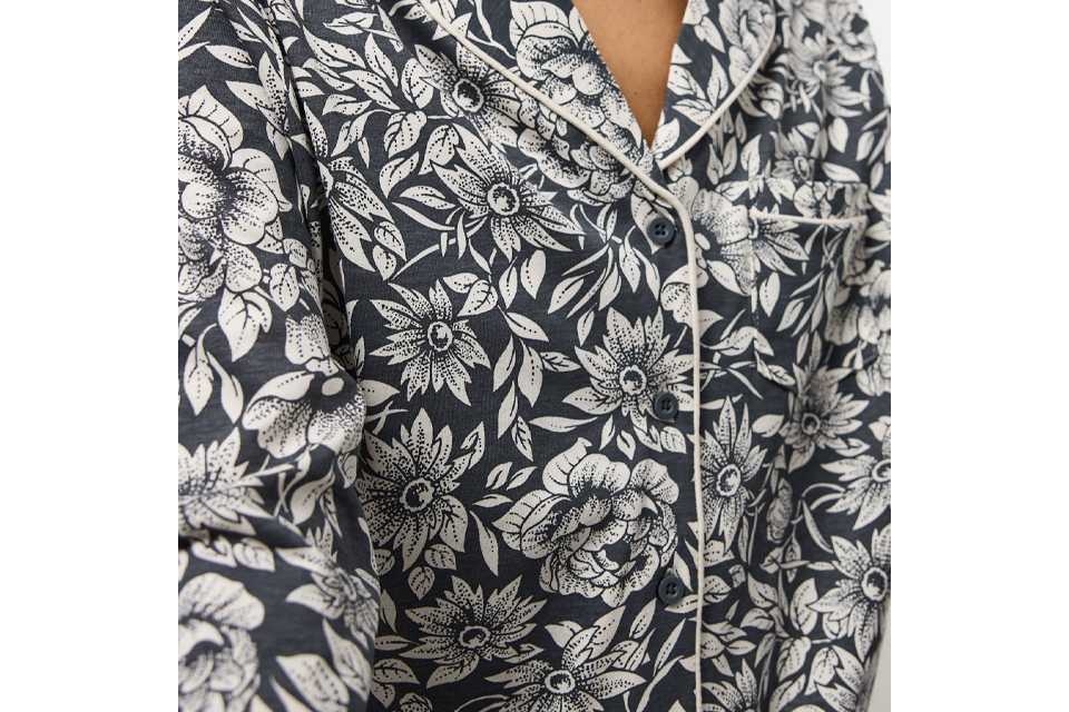 Woman wearing pyjama top with a black background and white flowers.
