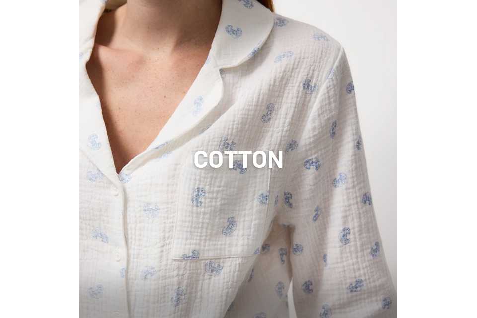 Close-up of a person wearing a white textured button-up shirt with a single chest pocket and a light blue paisley print pattern.