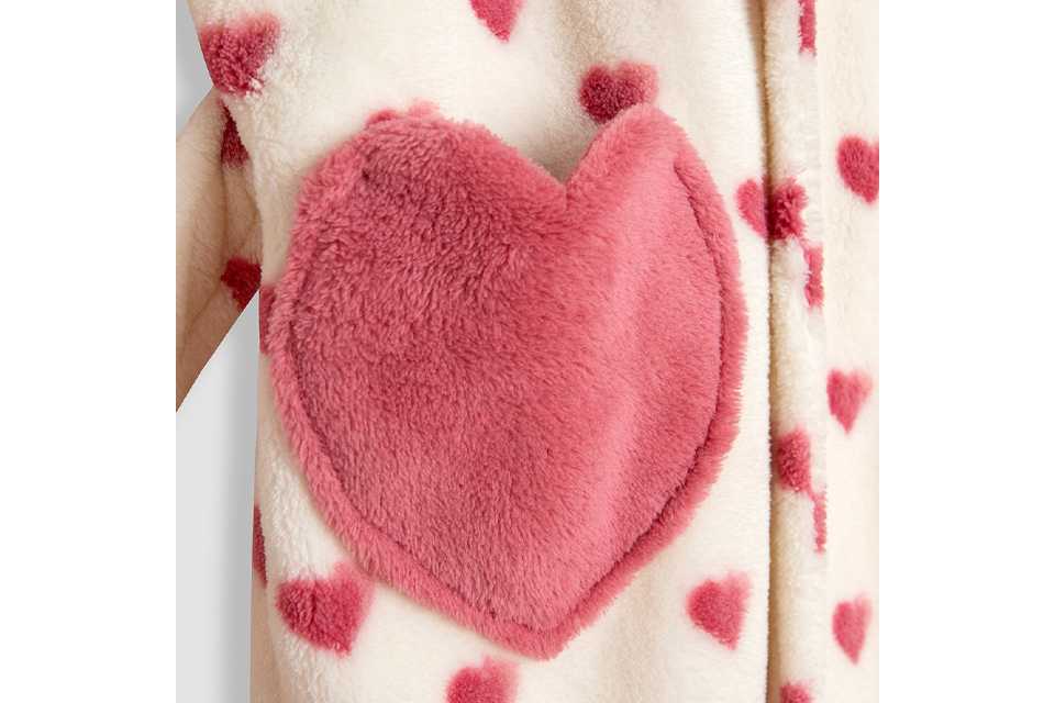 Close-up of cream fleece fabric with pink heart print and a large plush heart-shaped pocket detail.