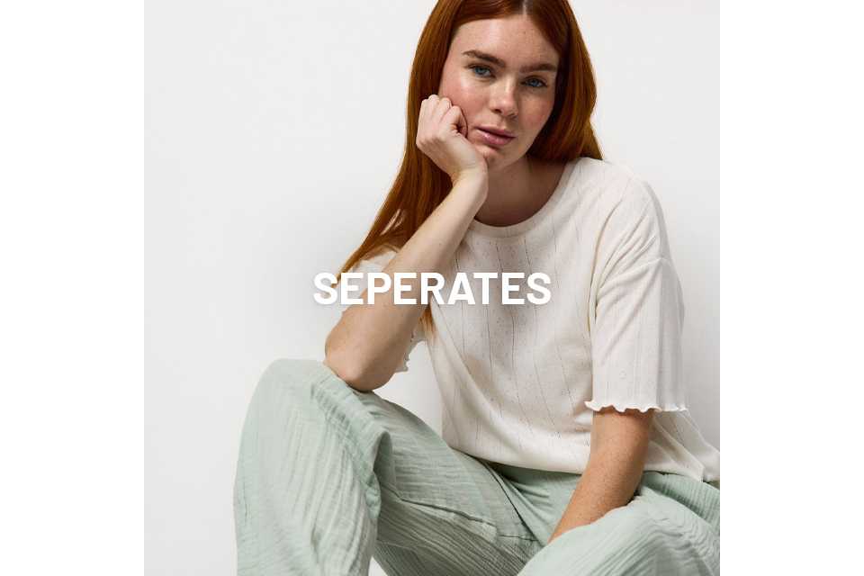 A woman wearing pjs with pale green bottoms and a neutral pyjama top.