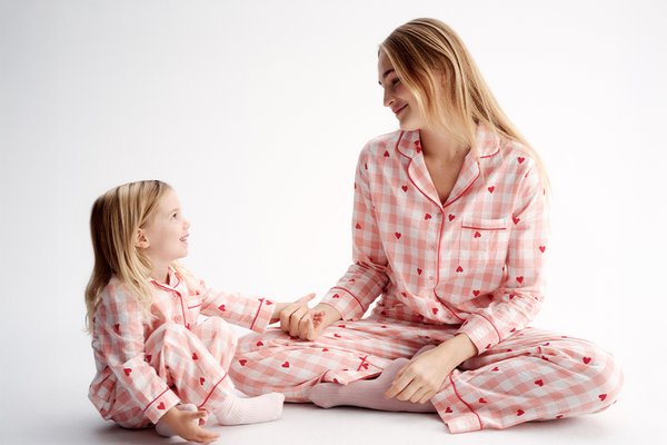 Person wearing long-sleeve button-up pyjamas with a black and white floral print, sitting against a plain white background.