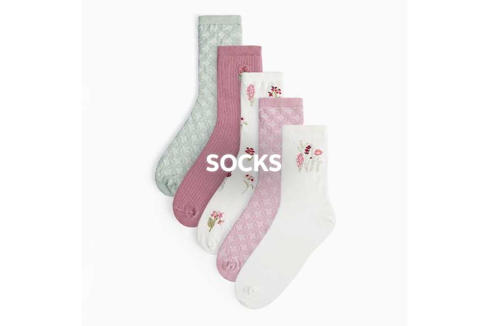 Assorted pastel socks in pink, white, and green with subtle patterns and small motifs.