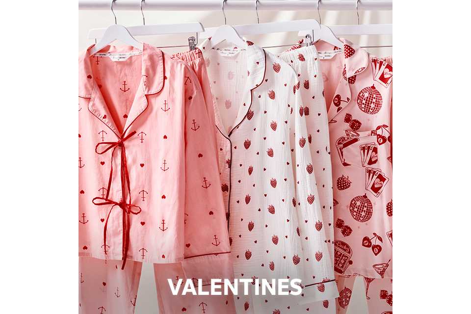 Selection of pink and white Valentine-themed pyjama sets with heart and anchor prints hanging on a rail.