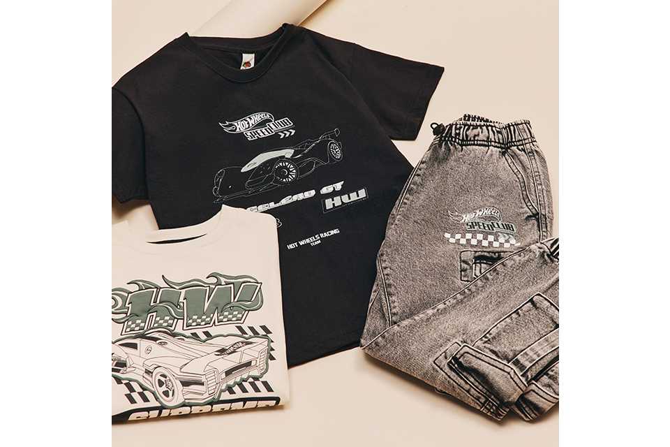 Flat lay of a black Hot Wheels T-shirt with car graphics, paired with grey joggers and additional printed tops.