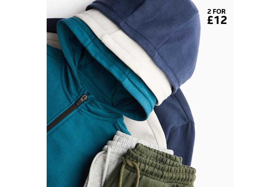 Pile of kids’ hoodies and joggers in blue, teal, grey, and khaki tones.